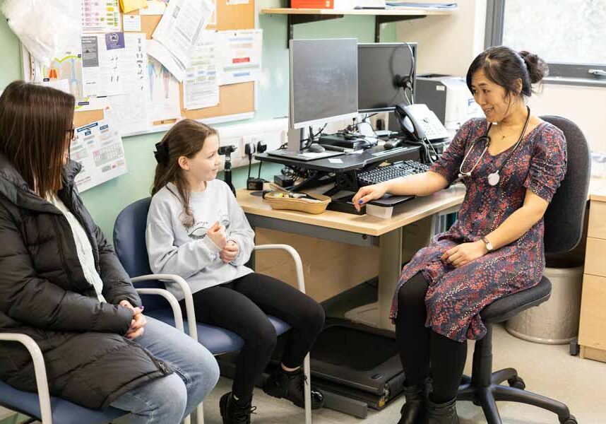 Child with parent meeting doctor in consultation room.